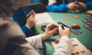 Giocatore che tiene in mano le carte di un gioco di strategia durante una sessione di gioco da tavolo in un club di giochi da tavolo offline con gli amici, godendosi un’esperienza di gioco in compagnia.