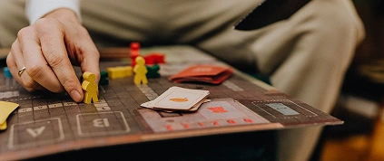 Un giocatore che sposta pedine di legno su un gioco da tavolo strategico con carte e pezzi da gioco, godendosi un'avvincente esperienza di gioco da tavolo con gli amici.